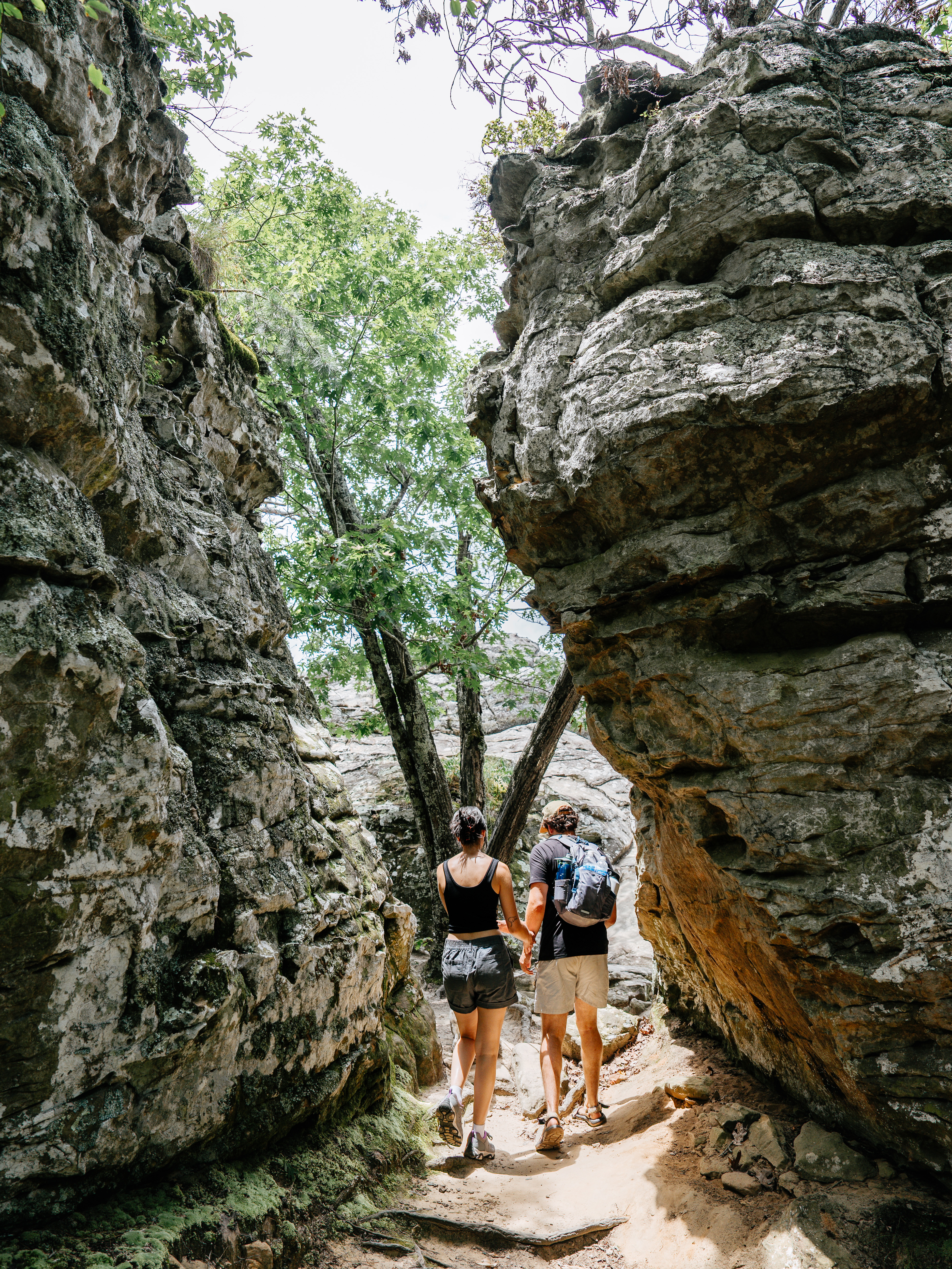 AA couple walking under a rock formation.